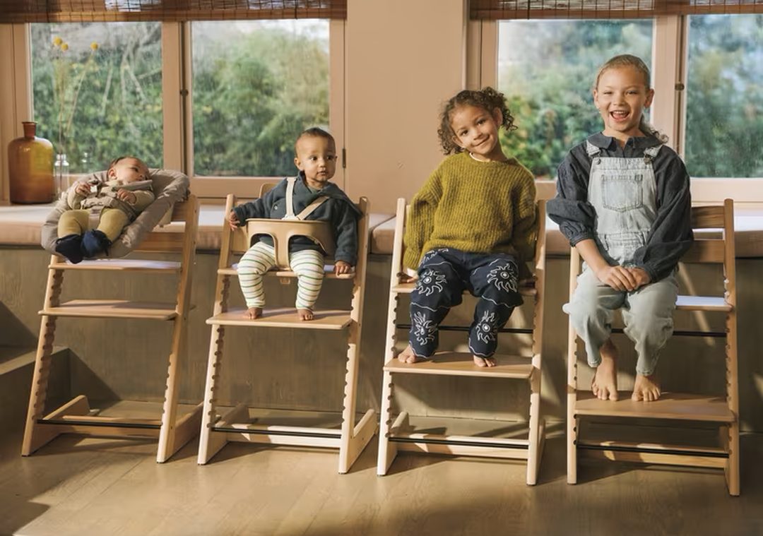 Vier Tripp Trapps naast elkaar met kinderen van baby tot schoolkind